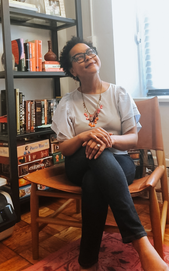 Jane Jones, PhD sitting in a chair with legs crossed, looking upwards